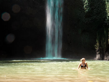 Full length of shirtless woman splashing water