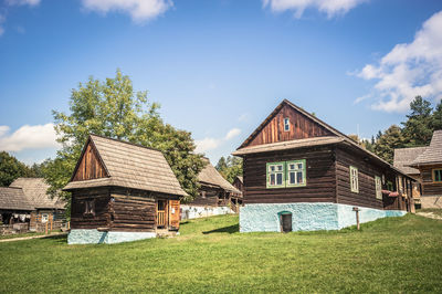 House on field by houses against sky