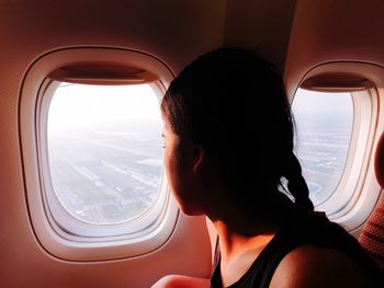 Mature woman looking through window in airplane