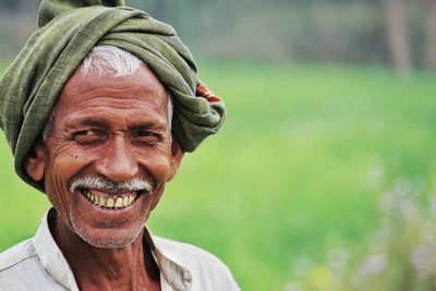 Close-up portrait of smiling farmer wearing turban on field