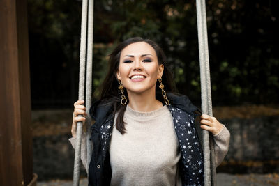 Portrait of young woman sitting on swing