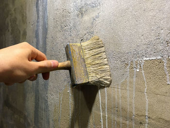 Midsection of person holding umbrella against wall