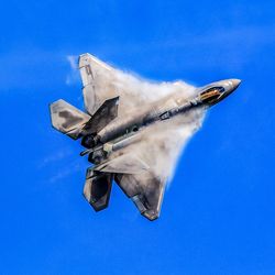 Low angle view of airplane flying against clear blue sky