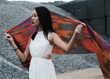 Young woman holding scarf against heap of gravels