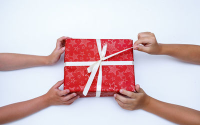 Low angle view of hand holding red box against white background