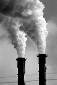 Smoke emitting from chimney against sky