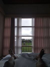 Man relaxing on bed seen through window
