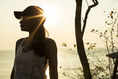 Young woman looking away against sky during sunset