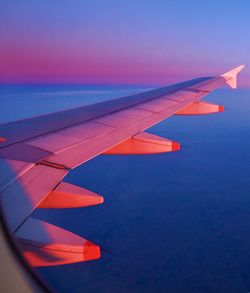 Airplane flying over sea against sky during sunset