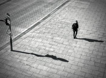 Rear view of woman walking on footpath during sunny day