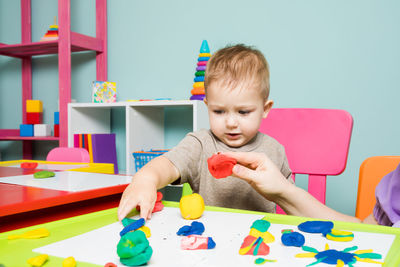 Cute boy with toys on table