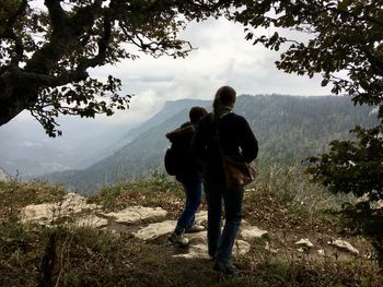 Rear view of friends standing on mountain against sky