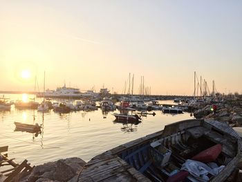 Boats moored in harbor at sunset