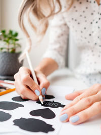 Midsection of woman holding paper with text on table