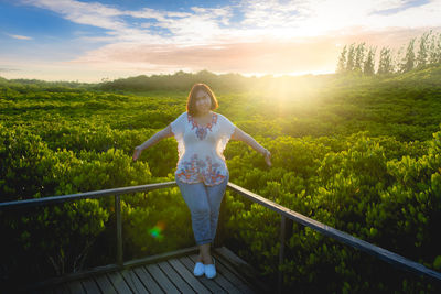 Portrait of woman standing by railing against sky