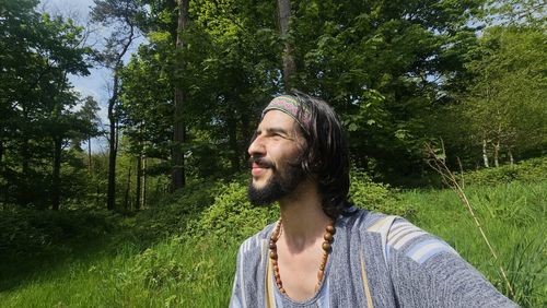 Portrait of young woman standing against trees