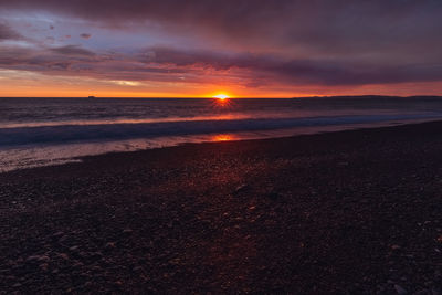 Scenic view of sea against dramatic sky during sunset