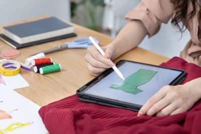 Midsection of woman using digital tablet on table