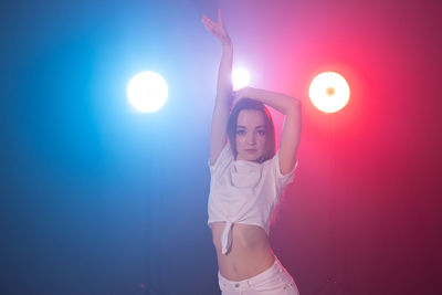 Full length of woman standing against illuminated wall