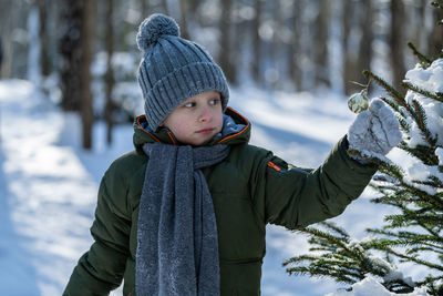 Cute boy touching plant during winter