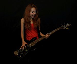 Young woman playing guitar against black background