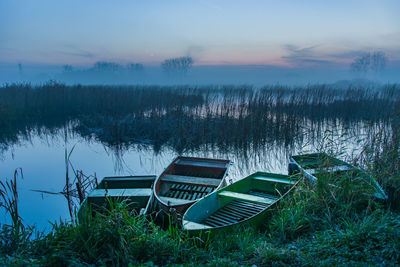 Boats on the shore, reeds and foggy lake, view after sunset