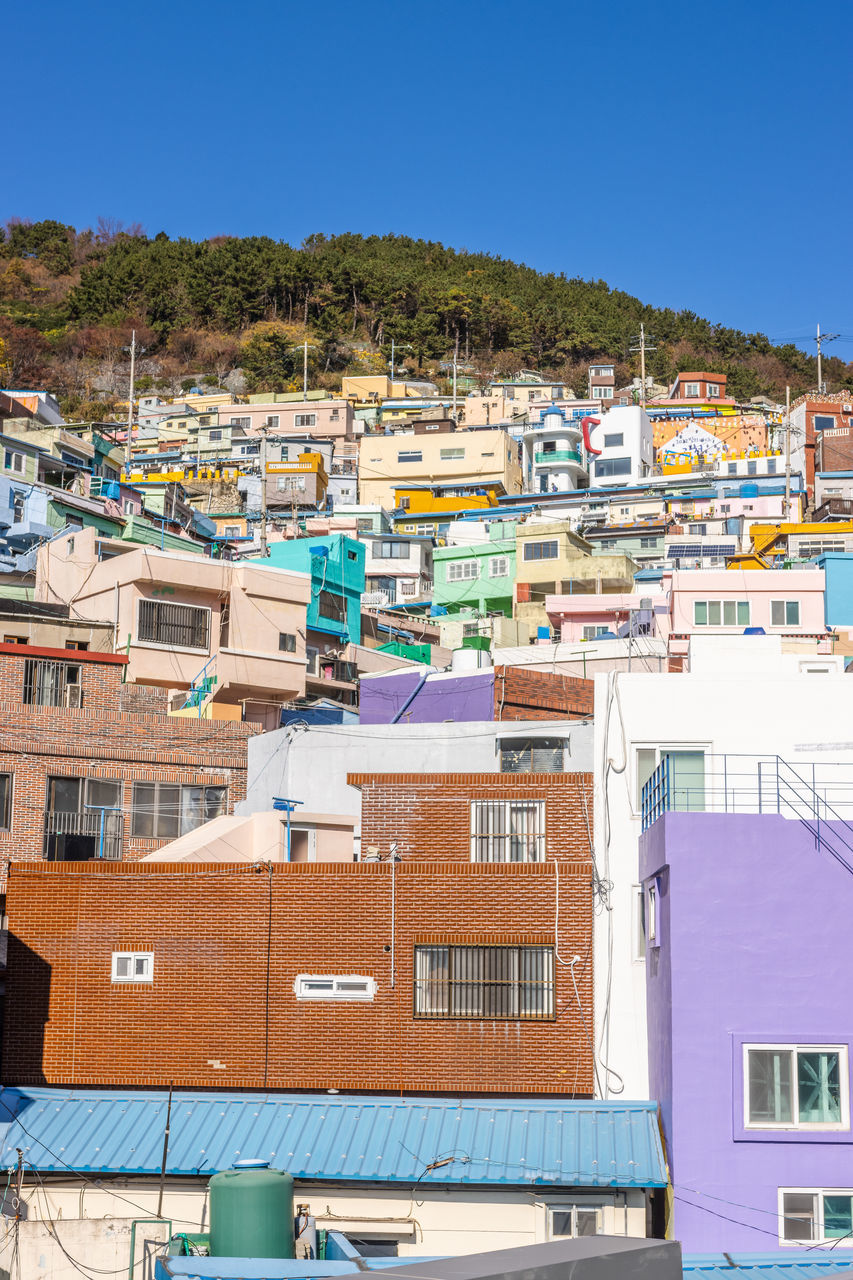architecture, building exterior, built structure, building, city, residential district, house, town, nature, water, clear sky, sky, land, no people, community, sea, travel destinations, neighbourhood, travel, blue, residential area, cityscape, day, multi colored, sunny, outdoors, roof, beach, tourism, high angle view, vacation, transportation, mountain, sunlight, apartment, urban area, environment