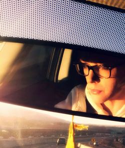Woman reflecting on rear-view mirror in car