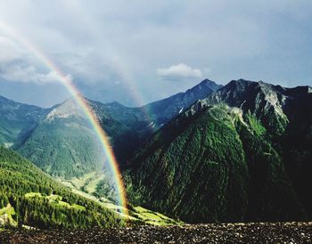 Scenic view of rainbow over mountains against sky