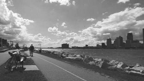 Rear view of people sitting in city against sky