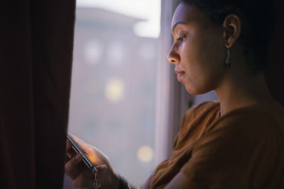 Young woman using phone by window