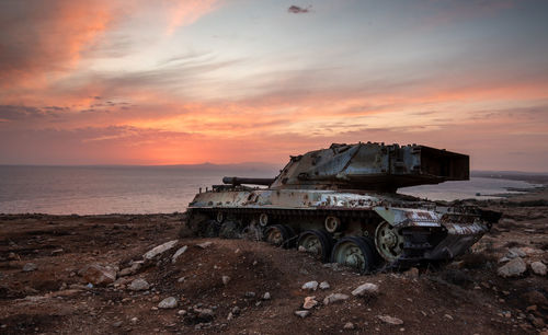 Old rusty abandoned military tank in the field at sunset