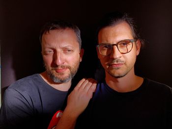 Portrait of man wearing eyeglasses against black background