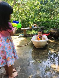 Siblings playing with squirt gun in yard