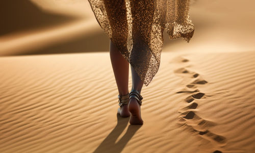 Low section of woman standing on sand at home