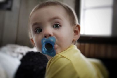 Portrait of cute baby girl sucking pacifier at home