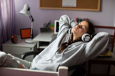 A relaxed teenager listens to music on wireless headphones.