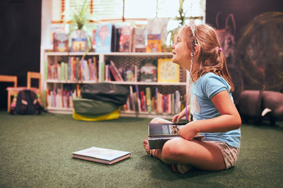 Primary schoolgirl doing homework in school library. student learning from books. back to school