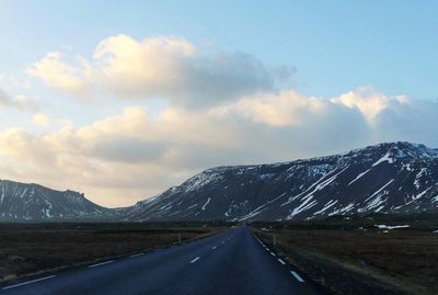 Road by mountains against sky