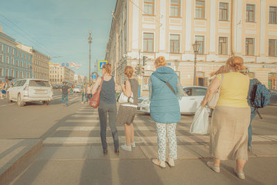 Rear view of women walking on street in city