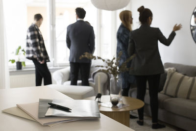 Agreement files with male and female real estate agents and clients in background at home