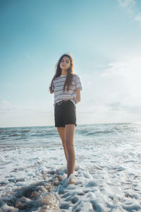 Full length of young woman standing on beach