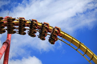 Low angle view of people on amusement ride against blue sky