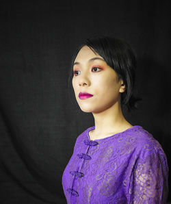 Portrait of a teenage girl looking away over black background