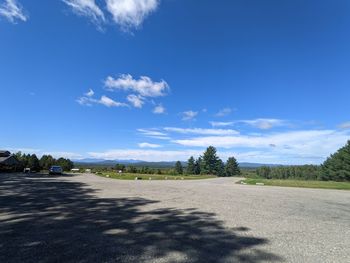 Road by trees against blue sky