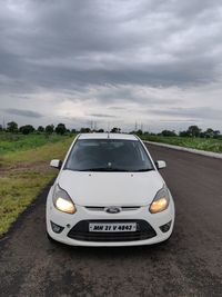 Car on road amidst field against sky