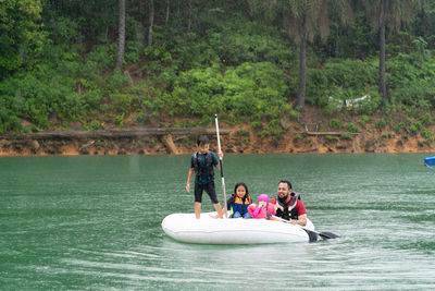 Man with children floating on inflatable ring over lake