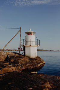 Lighthouse by sea against sky