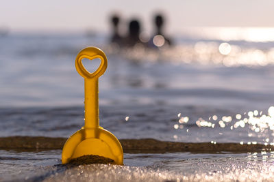 Close-up of yellow umbrella on beach against sky