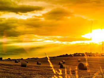 Hay bales on field against sky during sunset